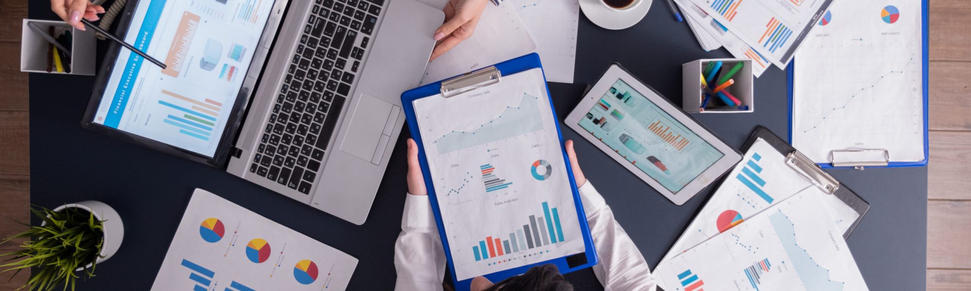 Top viewTop view of manager and employee doing teamwork in business office , looking at charts on laptop display. Finance paperwork with charts at workplace. Discusing financial plan.